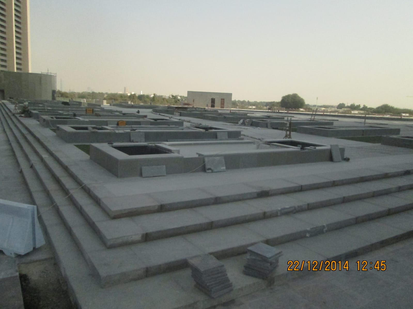 Large stone-paved podium plaza with planters during fit-out