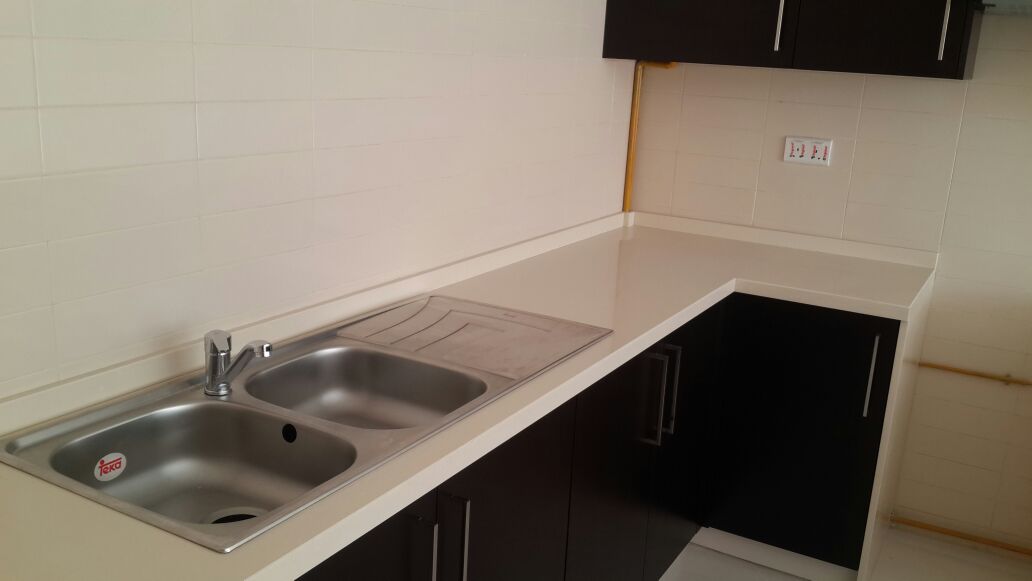Fabricated stone worktop installed over dark kitchen cabinetry