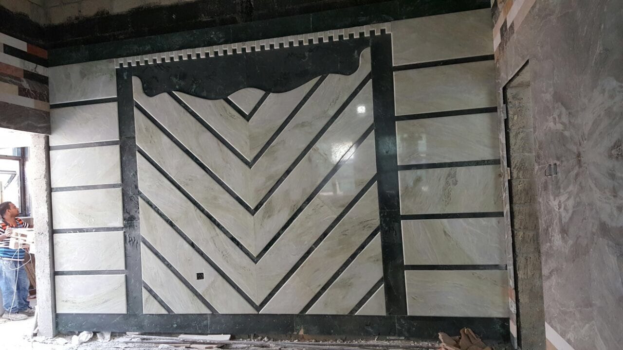 Book-matched marble feature wall with chevron pattern and dark stone borders