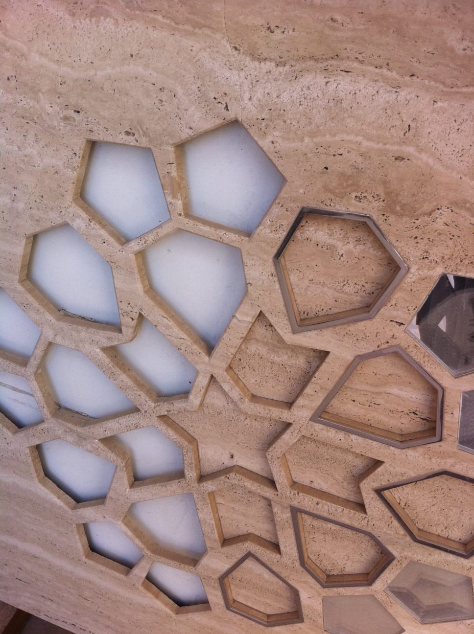 Backlit travertine lattice panel with geometric cut-outs